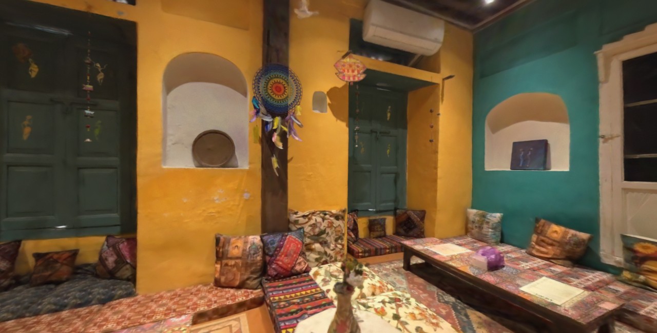 Captured interior of Maikada Cafe with yellow walls, green doors and seating
